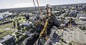 rappeler wearing a hard hat and industrial harness is suspended from ropes above the Richmond skyline